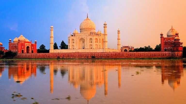 Taj Mahal in Agra spiegelt sich im Wasser bei Sonnenuntergang