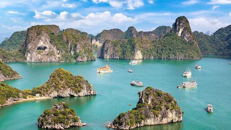 Halong-Bucht in Vietnam mit Kalksteinfelsen und Ausflugsbooten im türkisfarbenen Wasser