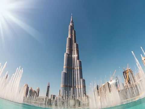Burj Khalifa ragt über die Wasserfontänen in Dubais Innenstadt in den blauen Himmel.