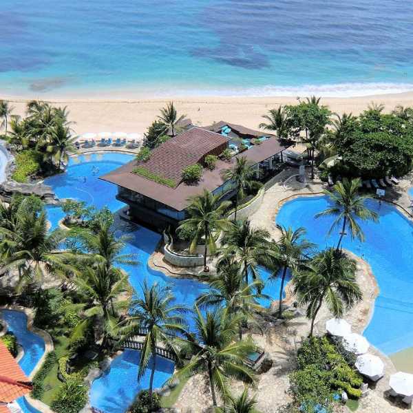 Luftaufnahme einer luxuriösen Hotelanlage mit mehreren Pools und direktem Strandzugang auf Bali.