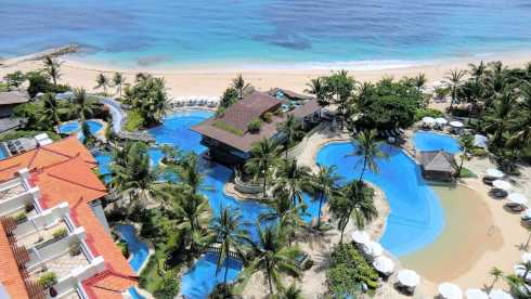 Luftaufnahme einer luxuriösen Hotelanlage mit mehreren Pools und direktem Strandzugang auf Bali.