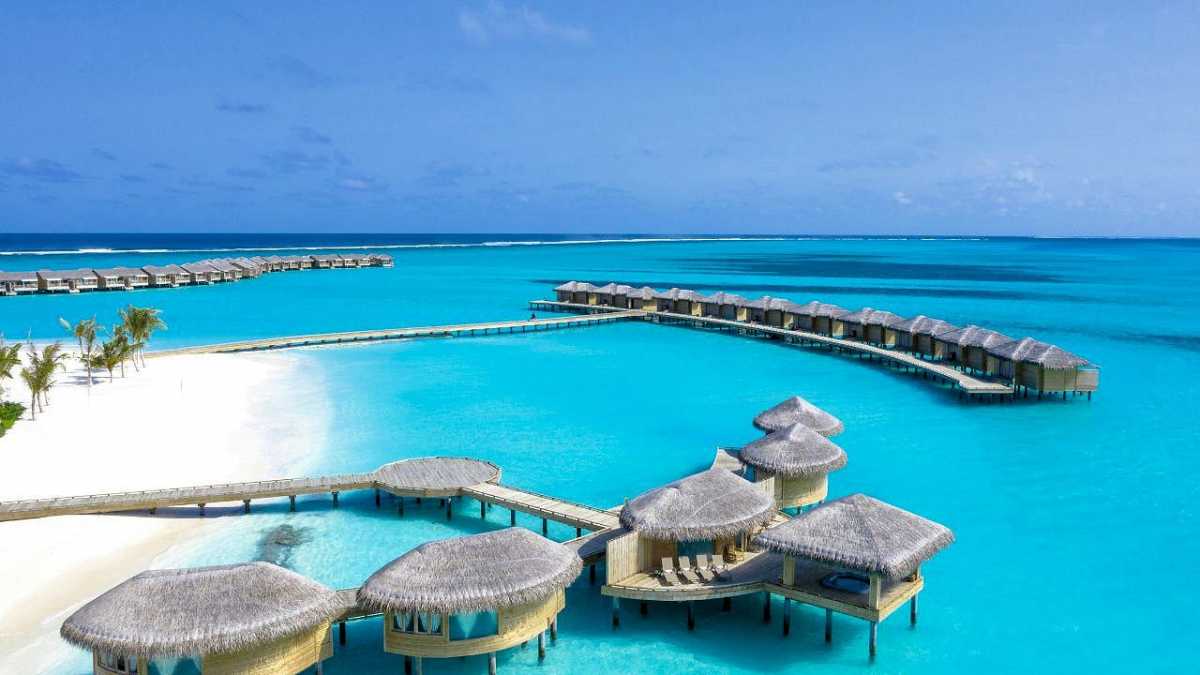 Luxusresort mit Wasserbungalows auf den Malediven, umgeben von türkisblauem Meer und weißem Sandstrand.