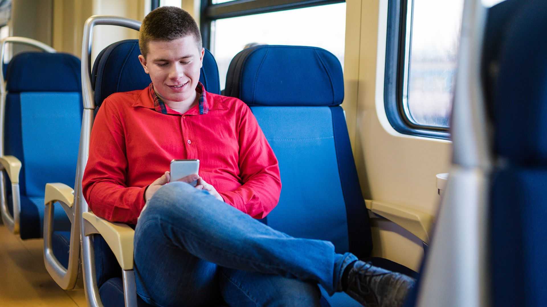 Reisender sitzt entspannt im Zug und nutzt sein Smartphone