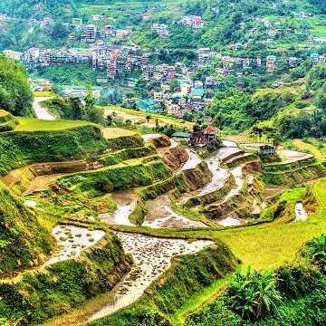 Blick auf die sattgrünen Reisterrassen von Banaue mit Dörfern im Hintergrund, Philippinen