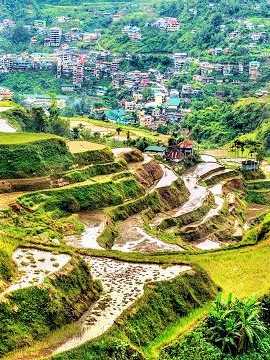 Blick auf die sattgrünen Reisterrassen von Banaue mit Dörfern im Hintergrund, Philippinen
