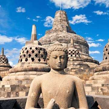 Stein-Buddhastatue vor den historischen Stupas des Borobudur-Tempels in Indonesien bei blauem Himmel