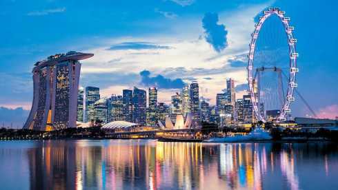 Singapur: Skyline an der Marina Bay mit Marina Bay Sands und dem leuchtenden Singapore Flyer in der Dämmerung