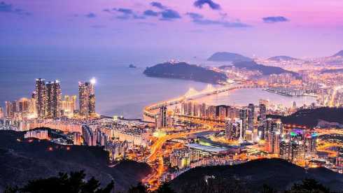 Busan, Südkorea: Blick über die erleuchtete Stadt und die Gwangan-Brücke am Meer in der Abenddämmerung