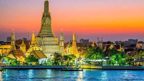 Thailand: goldene Buddhastatue vor reich verziertem Tempel unter blauem Himmel
