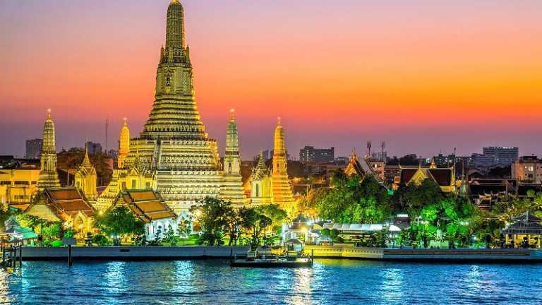 Wat Arun Tempel in Bangkok bei Sonnenuntergang mit beleuchteter Tempelanlage