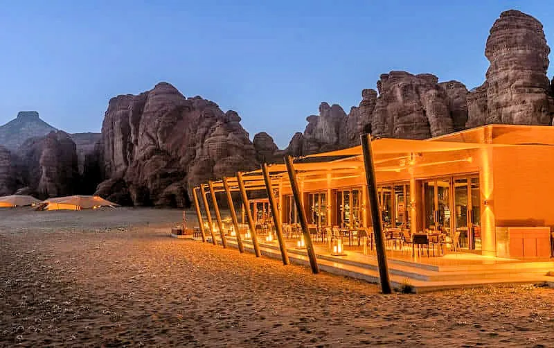 Luxus-Kombireise Saudi-Arabien: Beleuchtete Außenterrasse des Banyan Tree AlUla Resorts inmitten der antiken Sandsteinfelsen – JUREBU Weltentdecker-Highlight in AlUla.