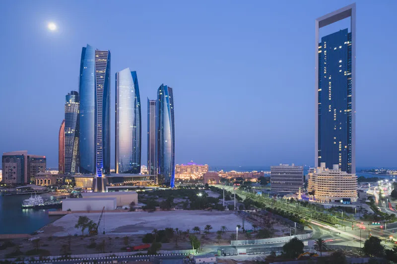 Luxus Kombireise Abu Dhabi Skyline bei Nacht mit beleuchteten Wolkenkratzern und Etihad Towers