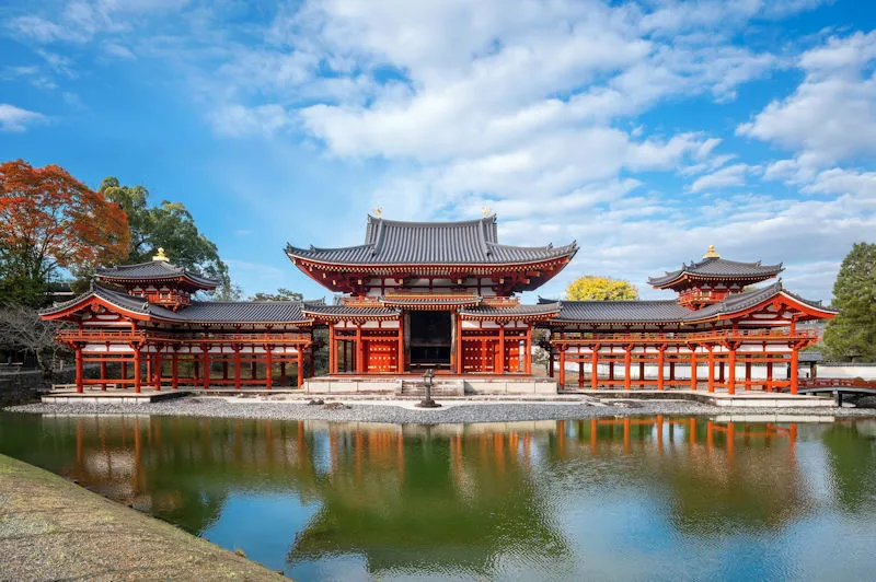 Luxus Reiseziel Japan - traditioneller roter Tempel mit Spiegelung im Wasser und herbstlicher Natur